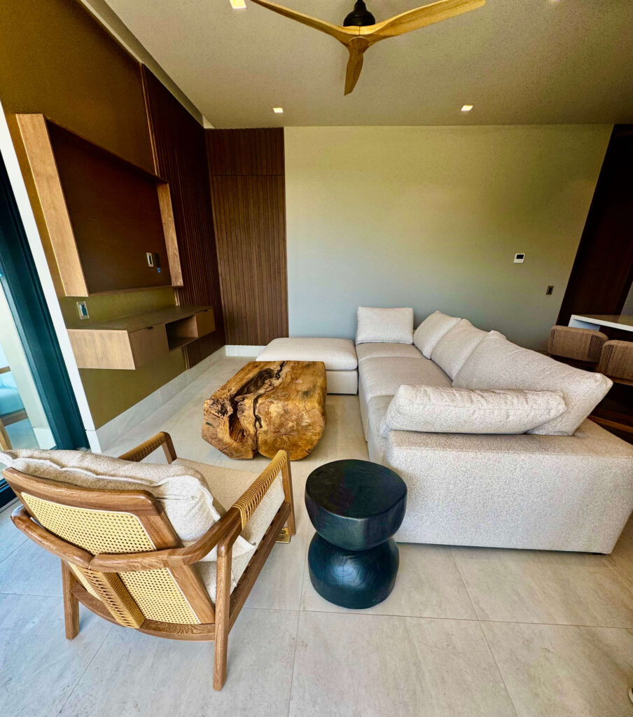 Modern Cabo condo living room with sectional sofa, teak accent chair, and solid wood coffee table